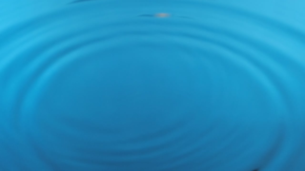 Splash. Round rain drops falling on smooth blue surface of water. Round transparent drop of water