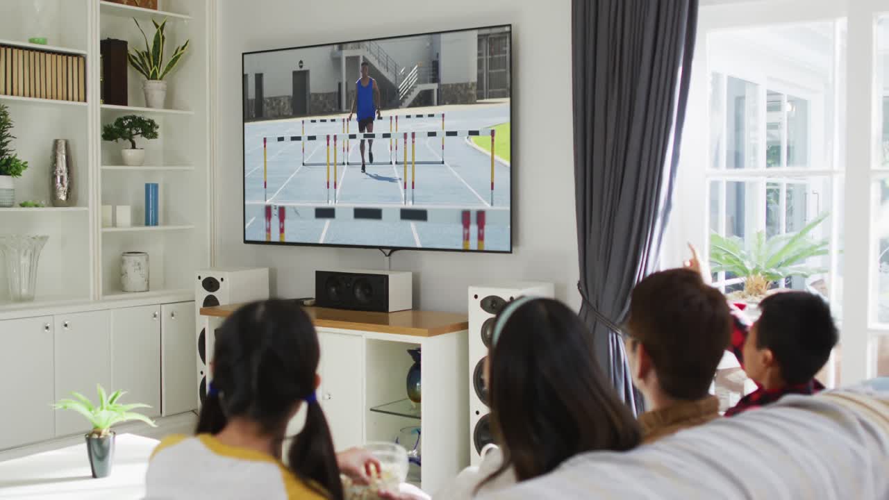 Composite of happy family sitting at home together watching athletics running event on tv