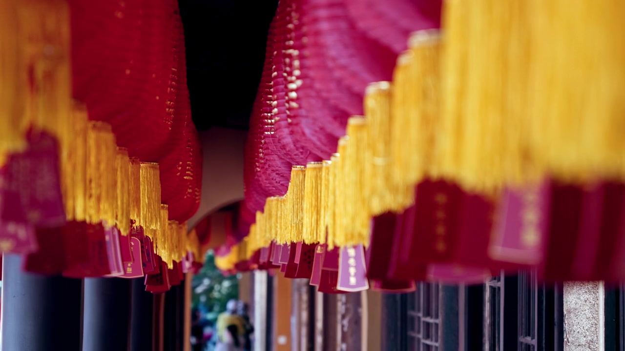 Lanterne rosse con nappe gialle pendono in un corridoio, creando uno spettacolo vivace. Ideale per documentari culturali o servizi di viaggio.