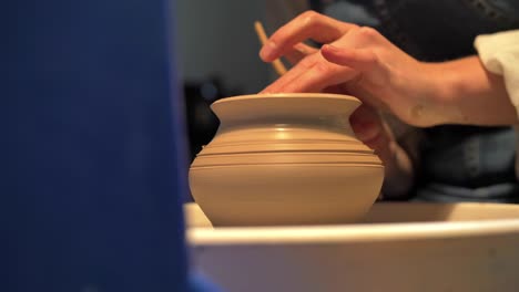 mujer hace una olla en una rueda de cerámica en un taller