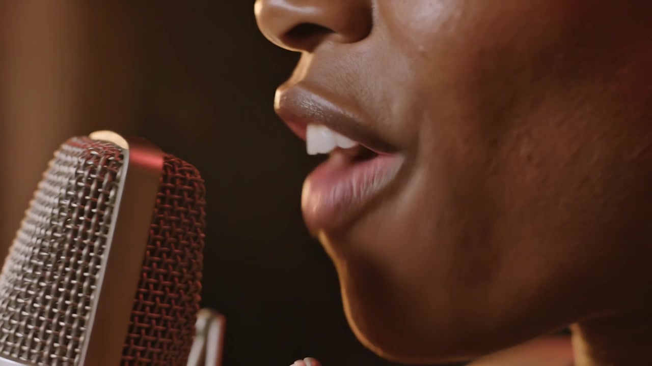 Singing woman starting recording, shaping vowel sounds at small studio, with microphone and ring