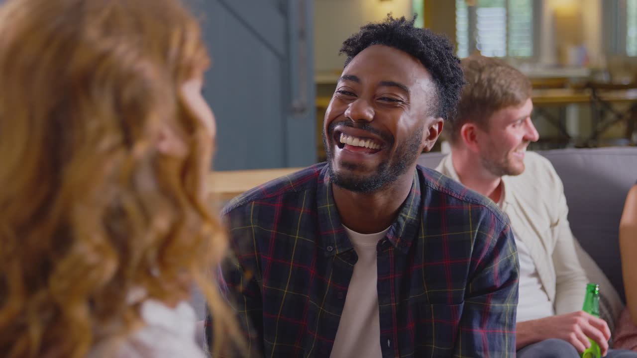 pareja joven sentada en el sofá en casa hablando y disfrutando de bebidas juntos