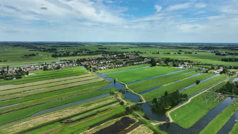 Hohe-Breite-Luftaufnahme-Eines-Typischen-Holländischen-Polderlandes-Mit-Vielen-Kleinen-Kanälen-Und-Slagenlandschap,-Die-Eine-Stadt-Mit-Blauem-Himmel-Und-Wolken-In-Der-Krimpenerwaard-region-Der-Niederlande-Umgeben