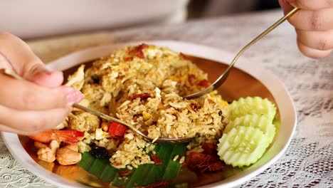 hands serving pineapple rice with shrimp and vegetables