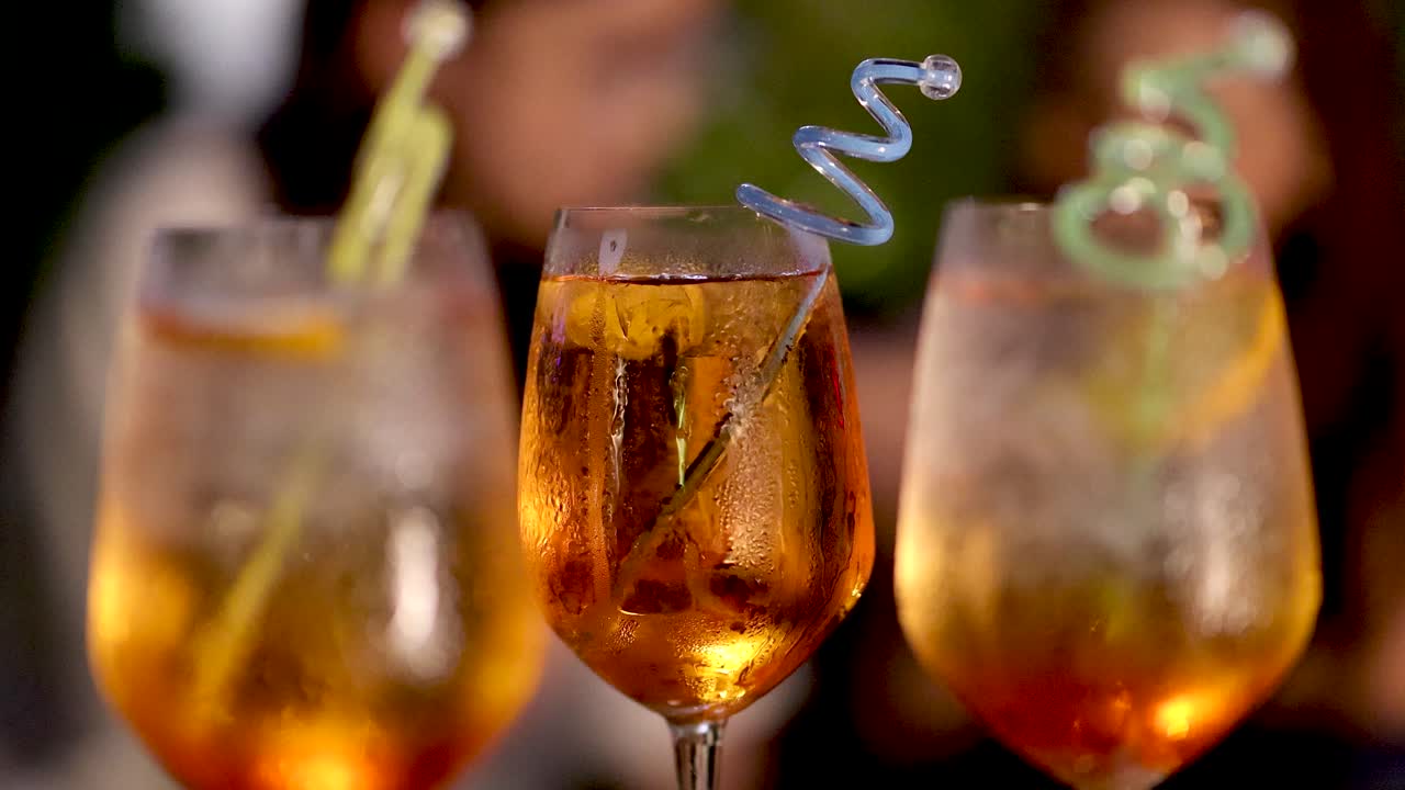 Three Negroni cocktails clinked together outdoors, warm ambient lighting, shallow depth of field, celebratory mood