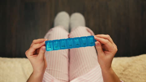 woman holding a weekly pill organizer in pajamas