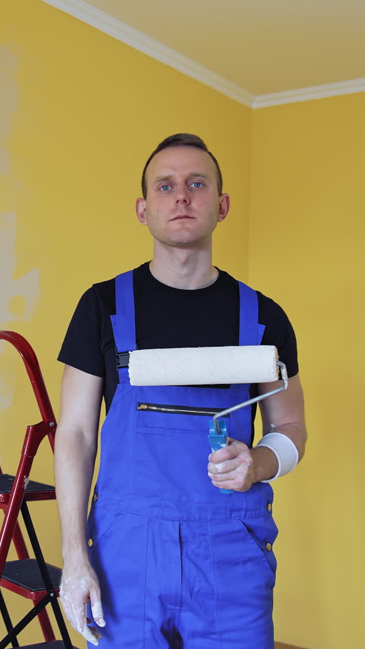 Man painting with roller. Workman in the uniforms painting the walls with paint roller. Vertical video