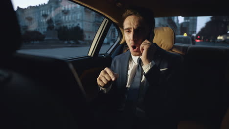 Annoyed-businessman-swearing-on-smartphone-in-dark-salon-of-luxury-automobile.