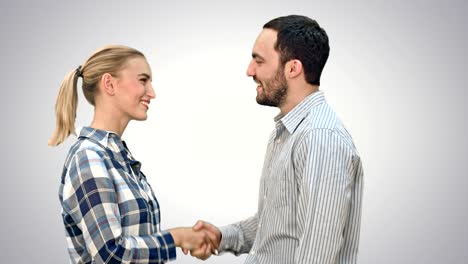 teen people shaking hands and looking at camera on white background