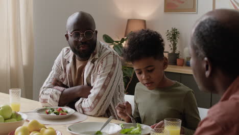 black men and boy eating lunch at home