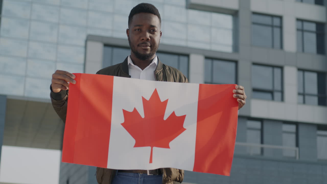 Man holding Canadian flag in front of modern building