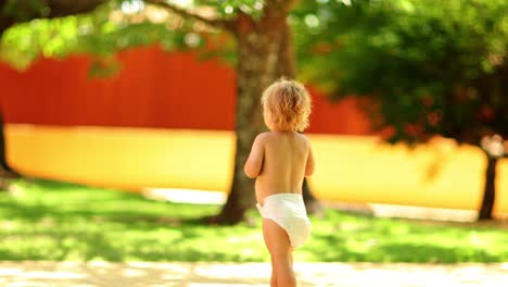 candid shot of infant toddler boy child walking outdoors with diapers in 4k clip resolution
