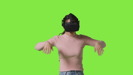 mujer con auriculares de realidad virtual e interactuando contra el fondo del estudio de pantalla verde nadando y buceando