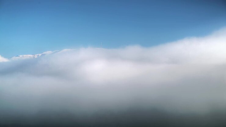 Time Lapse of Thick Fog Rolling Over Snowy Mountain Peak