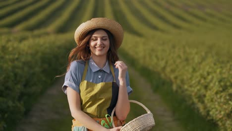 pretty young woman in a field dressed in the form of a gardener walking with a basket