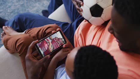 Compuesto-De-Padre-E-Hijo-En-Casa-Viendo-Un-Partido-De-Hockey-En-Un-Teléfono-Inteligente