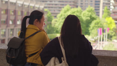 Rear-View-Of-Two-Young-Female-Friends-Visiting-The-Barbican-Centre-In-City-Of-London-Together