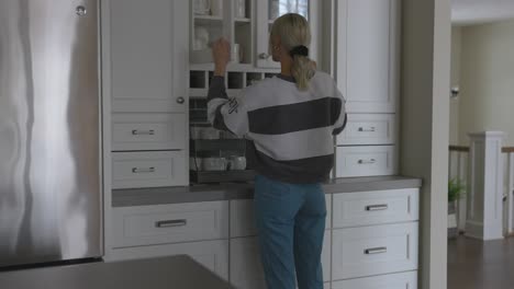 Frau-Geht-Zum-Schrank,-Um-Sich-Eine-Tasse-Zu-Holen-Und-Eine-Tasse-Kaffee-Zu-Kochen