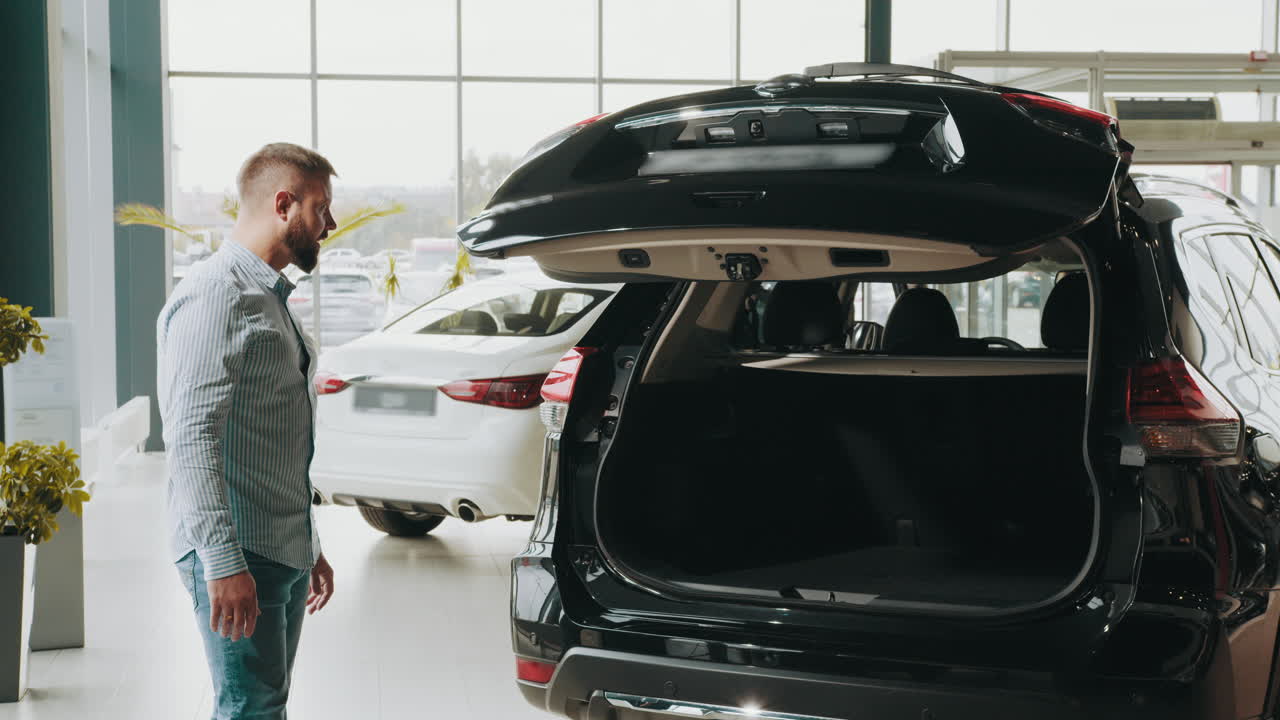hombre comprobando el maletero de un suv negro en un concesionario