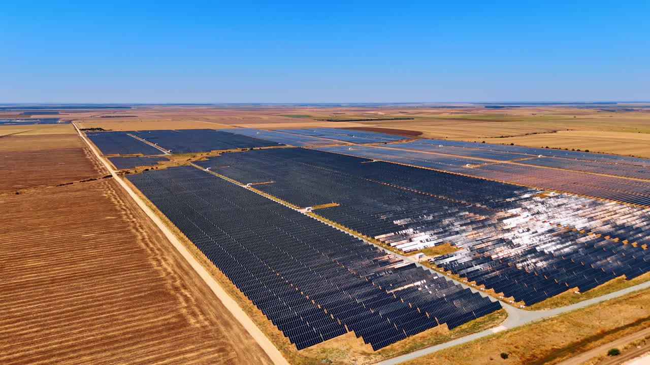 Photovoltaic solar farm covering dry fields. Aerial view of a solar farm with photovoltaic panels installed across the dry agricultural land