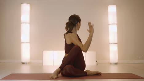 woman doing seated spinal twist pose on mat. fit girl performing yoga in studio