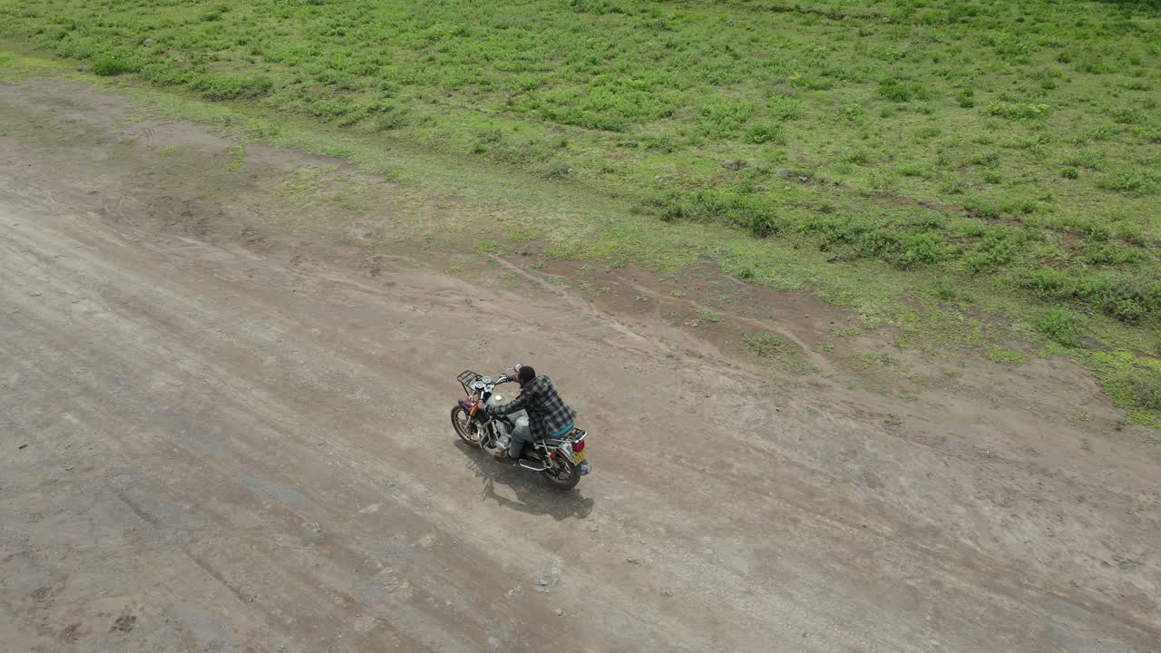 Vista aerea di un uomo in moto su una strada sterrata di campagna a Loitokitok, Kenya