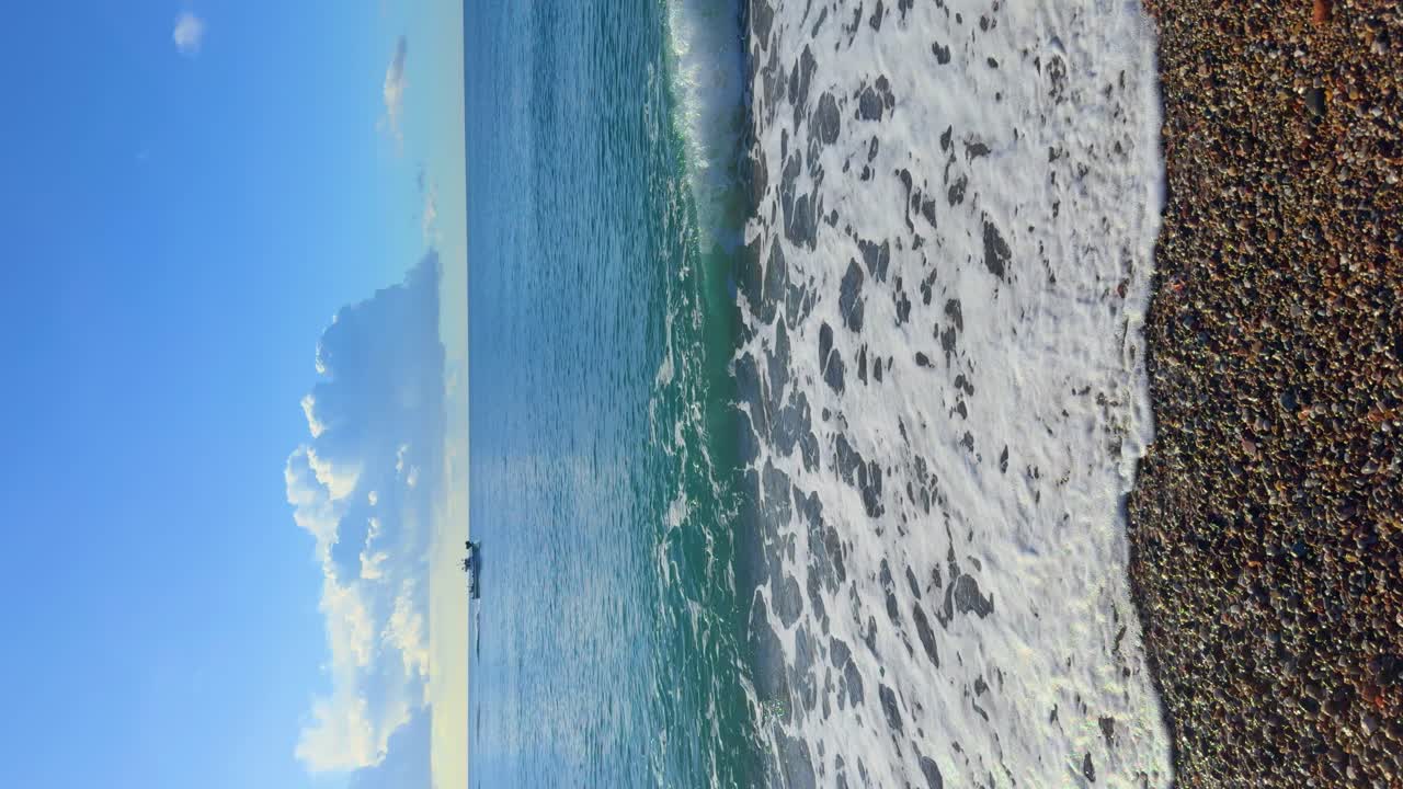 Immagine verticale di una spiaggia con cielo per spazio di copia in 4K, con una barca che passa sullo sfondo