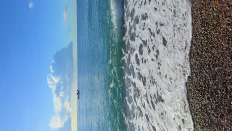 Vertical-image-of-a-beach-with-sky-for-copy-space-in-4K-boat-passing-in-the-background