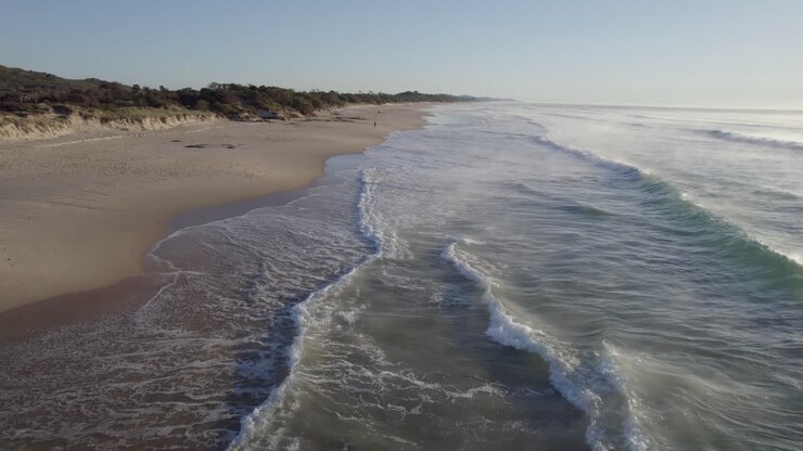 Meereswellen am sandigen Strandabschnitt bei Sonnenaufgang – Coolum Beach an der Sunshine Coast, Queensland, Australien.
