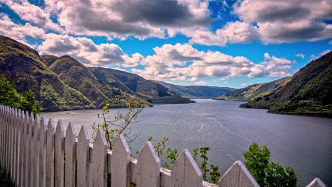 Time-lapse-shot-of-flying-clouds-over-Fjord-surrounded-by-green-mountains-in-Norway---Spectacular-aerial-view-from-apartment-garden-with-beautiful-landscape-view