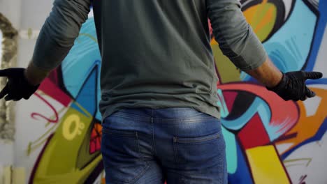 artista de graffiti de pie frente a la pared de graffiti 4k