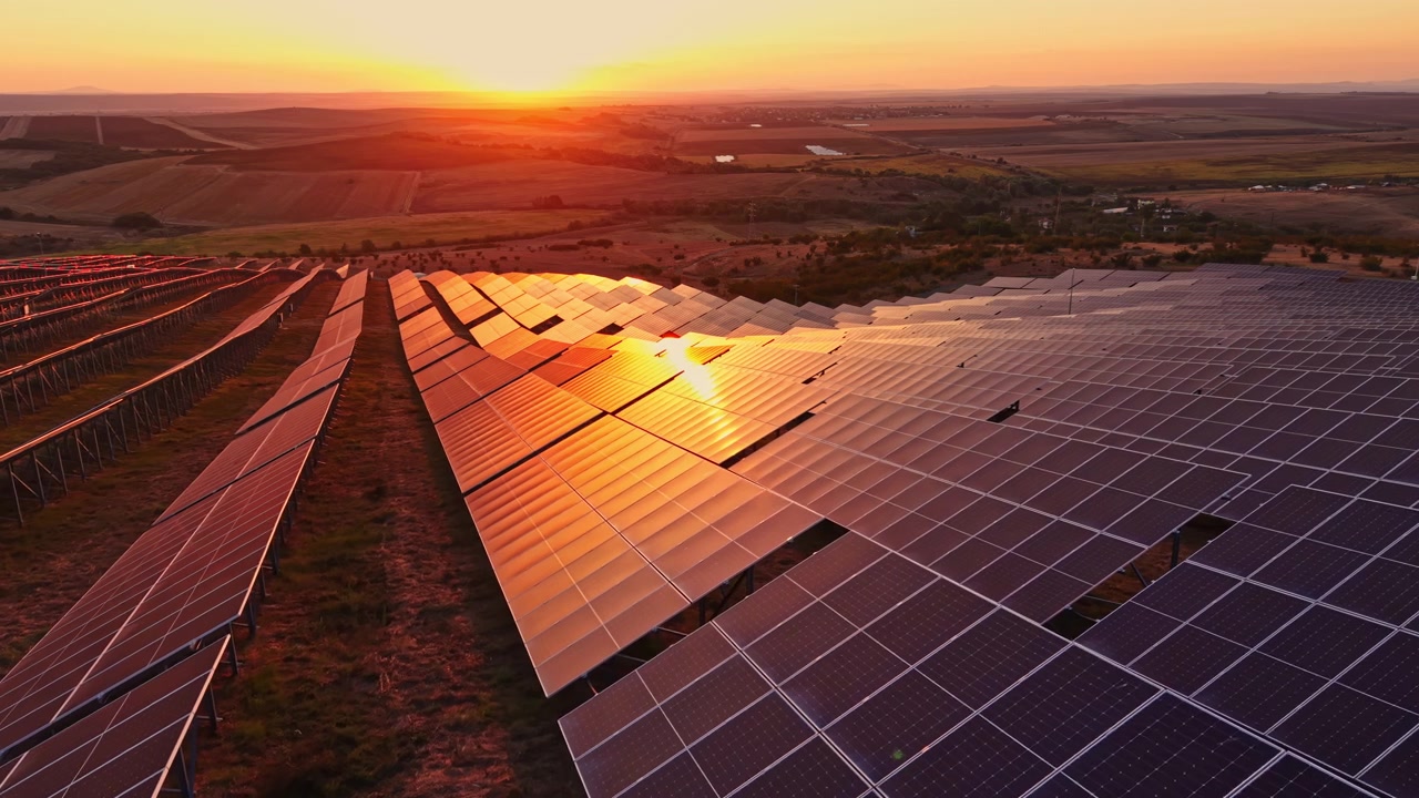Udsigt til solnedgang over solpaneler på en vedvarende energipark i landligt landskab