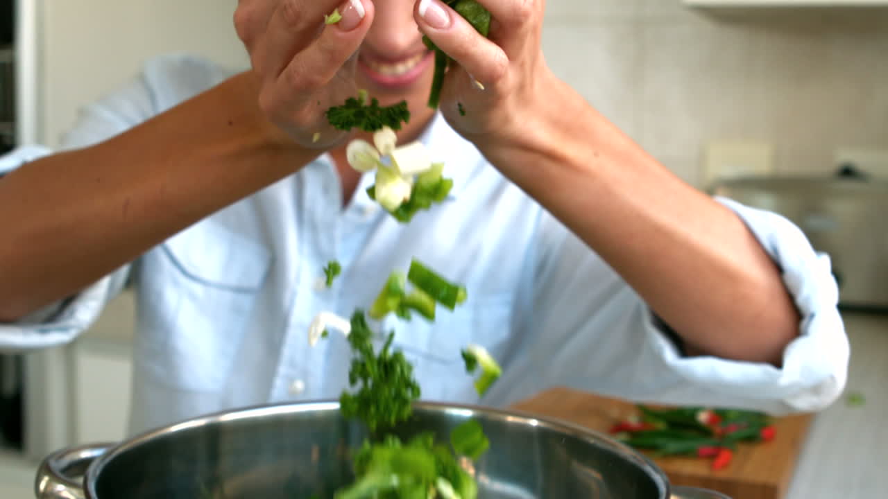 mujer añadiendo verduras picadas a la olla