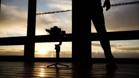 person silhouette calibrate gimbal stabilizer in studio during golden hour