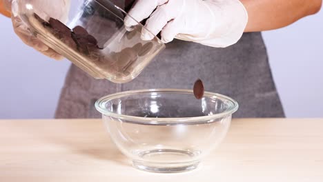 persona vertiendo fichas de chocolate en un cuenco de vidrio