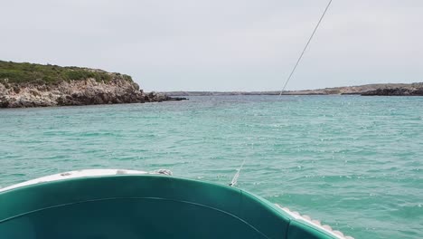 a boat floats in clear turquoise waters near the cliffs of cala pudent, spain