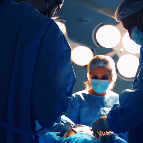 group of surgeons. doctors in blue uniform perform an operation to patient against medical lamp in the surgical room. medical procedure in clinic.