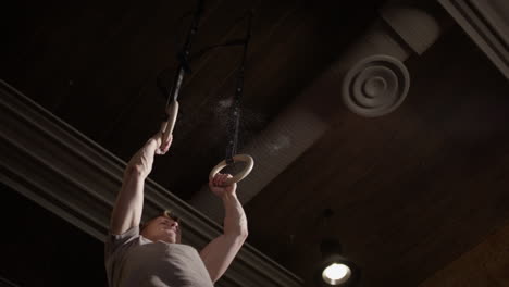 guy use momentum to perform pull up with crossfit gymnastic rings, upwards slomo