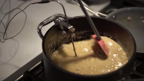 a young girl stirs a caramel mix heating up on the stove while baking millionaire shortbread cookies-5