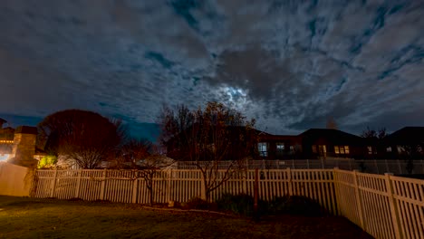 watching the full moon rising over a typical suburban neighborhood on an overcast night - tilt up time lapse