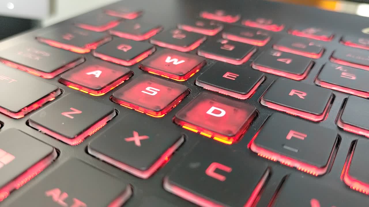 Laptop keyboard close-up. The most common gaming keys, W, A, S, and D, used for directional input, known as the WASD keys. Has the red backlight.
