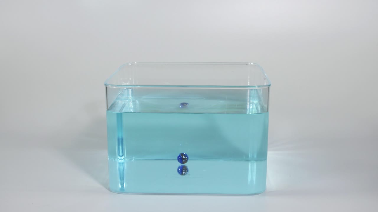 caída secuencial de bolas azules en un tanque de agua