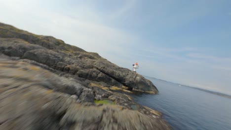 vuelo aéreo a lo largo de la costa del fiordo con un pequeño faro en noruega durante el verano