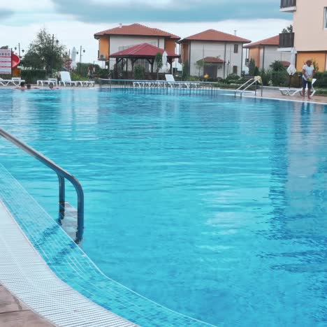 personas sentadas a la orilla de la piscina de un resort durante las vacaciones de verano