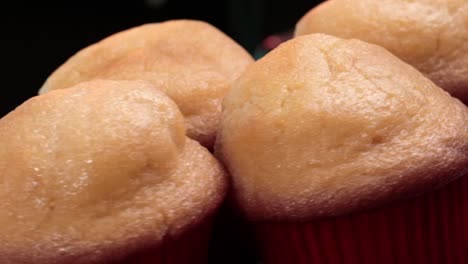 primer plano de muffins suaves y dorados en revestimientos rojos, recién horneados y listos para disfrutar