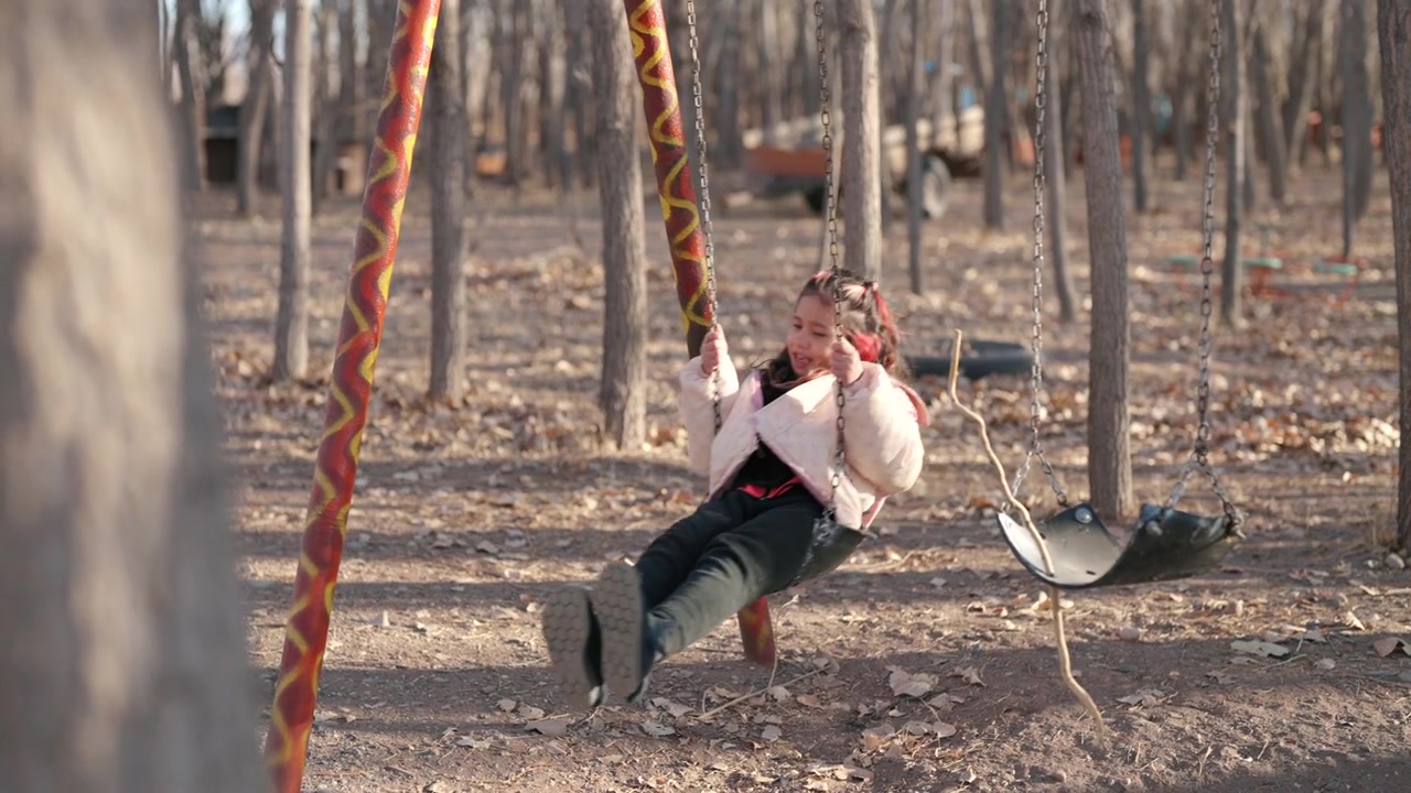 Ragazza che dondola in un parco con uno sfondo di foresta e un primo piano sfocato e morbido.
