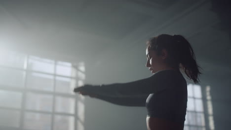 woman stretching body before crossfit workout in gym. girl raising hands