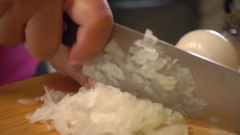 manos cortando una cebolla blanca en una tabla de cortar
