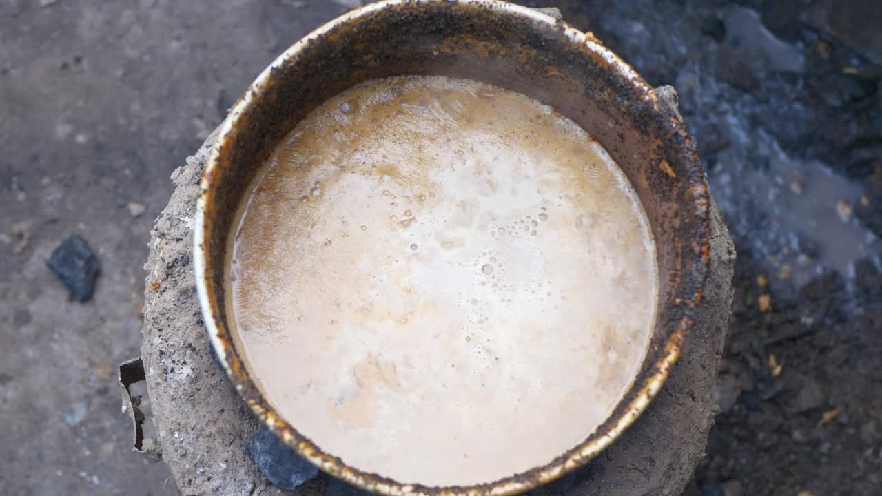 Gotująca się herbata mleczna na glinianym piecu węglowym, uchwycająca rustykalne smaki, ciepło i ponadczasowy urok autentycznej wiejskiej kuchni.