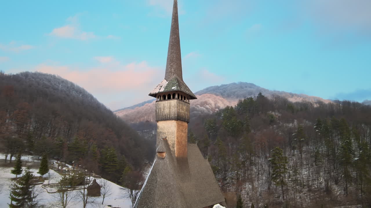 Dronebillede i fugleperspektiv af Barsana-klosteret i Rumænien. Hovedkirke, besøgende, bakker dækket af bar skov og sne, vinter.